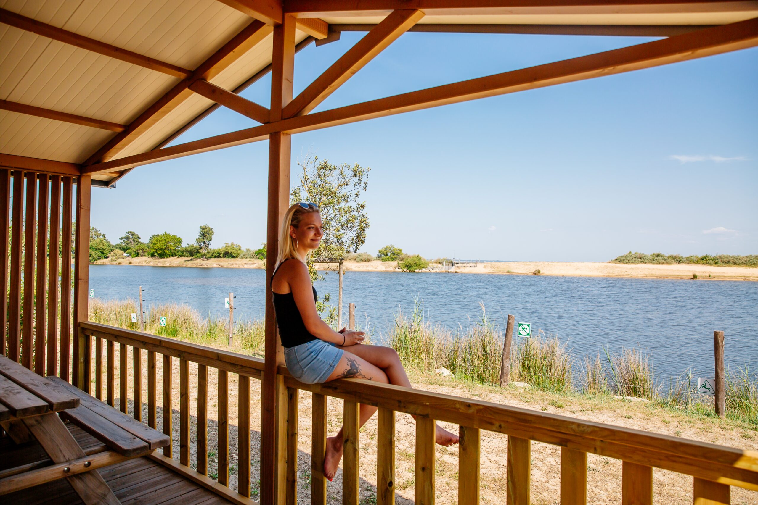 Une femme regarde le Bassin posé sur une rambarde dans le camping des viviers. 