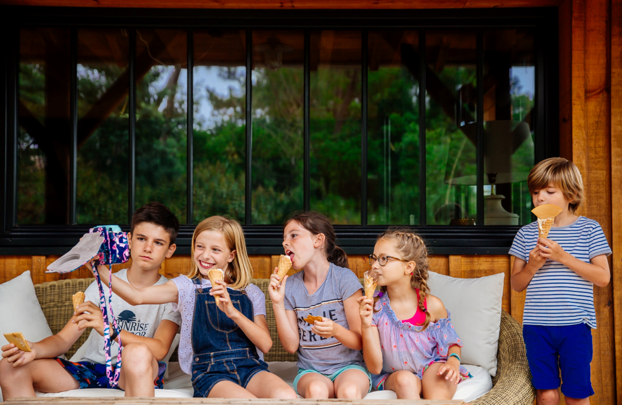 un groupe d'enfant mangent des glaces sur la terrasse d'une maison. 