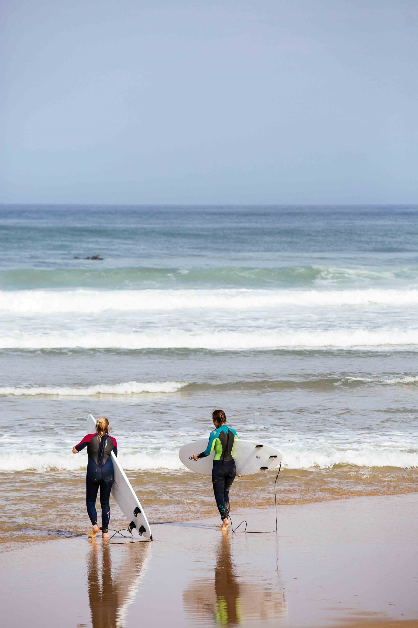 Deux surfeuses se préparent à rentrer dans l'eau. 