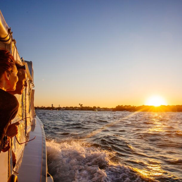 Une femme regarde le coucher de soleil sur son bateau pendant la traversée du bassin.
