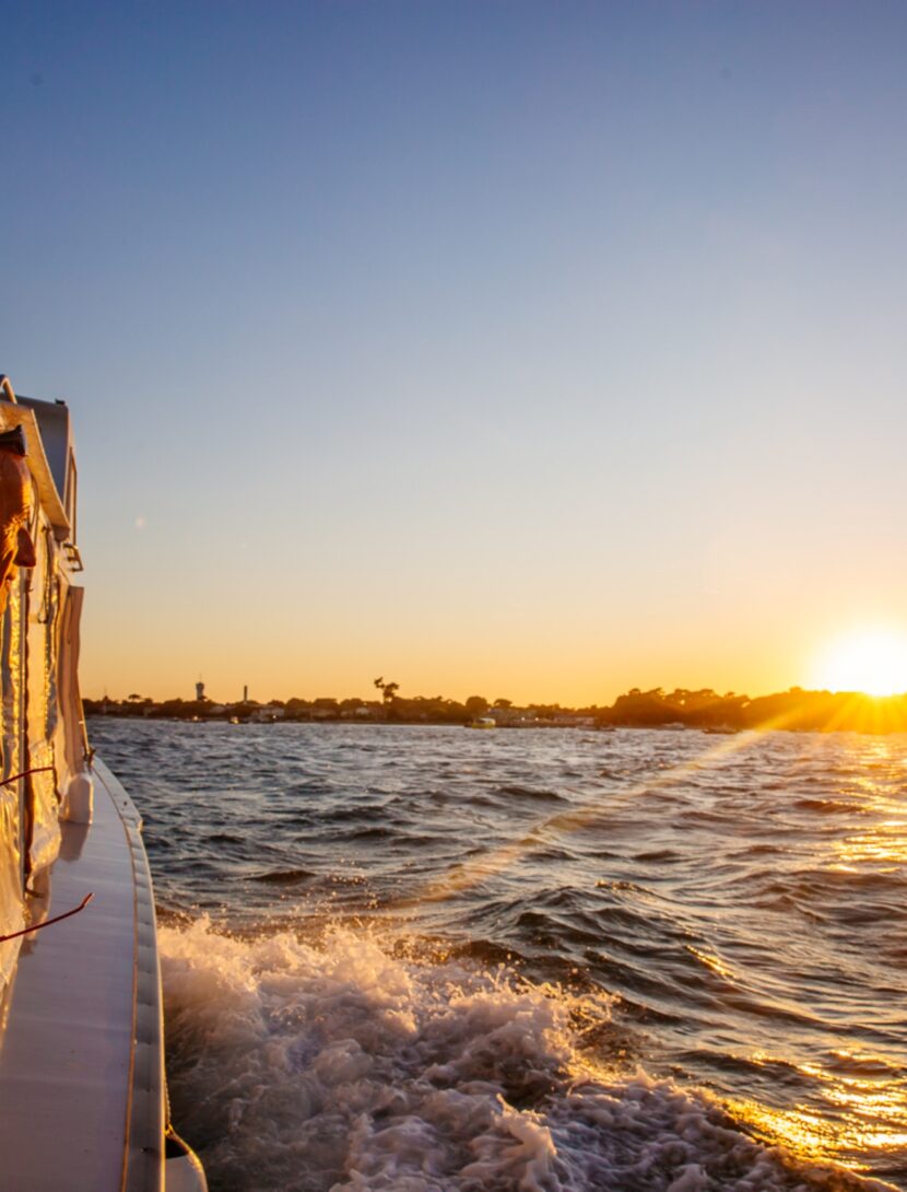 Une femme regarde le coucher de soleil sur son bateau pendant la traversée du bassin.