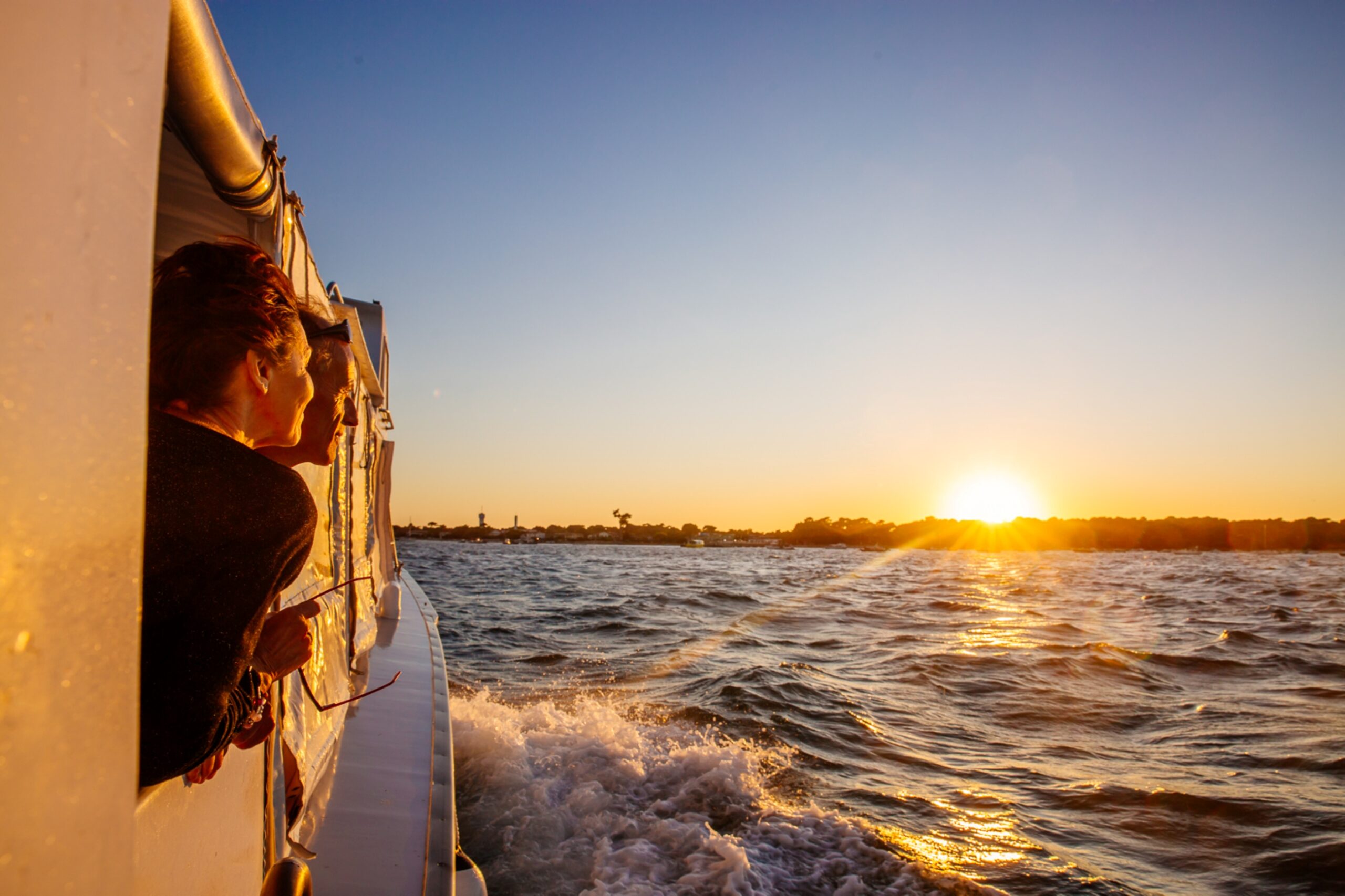 Une femme regarde le coucher de soleil sur son bateau pendant la traversée du bassin.