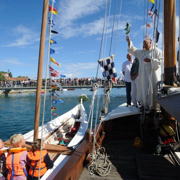 Deux bateaux participent à la fête de la Mer : l'un accueille un prêtre, tandis que l'autre est rempli d'enfants, incarnant l'esprit festif de cette célébration.