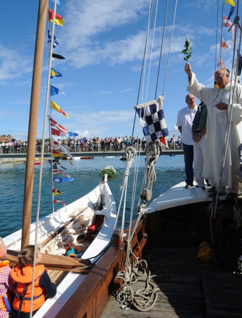 Deux bateaux participent à la fête de la Mer : l'un accueille un prêtre, tandis que l'autre est rempli d'enfants, incarnant l'esprit festif de cette célébration.
