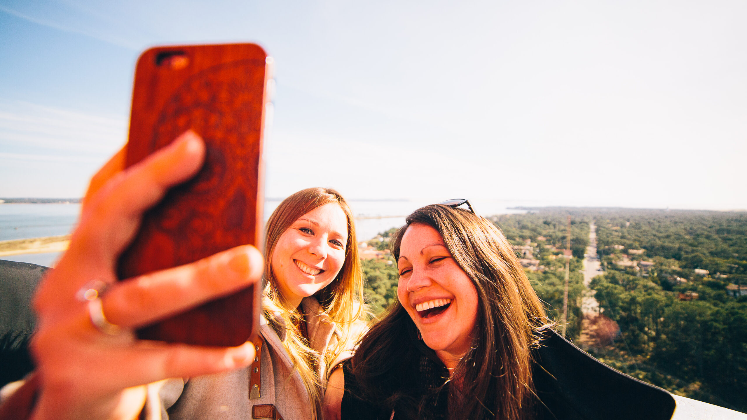 Deux amies, remplies de joie, immortalisent leur moment au sommet du phare en prenant une photo souvenir, avec une vue imprenable qui ajoute à la magie de l'instant.