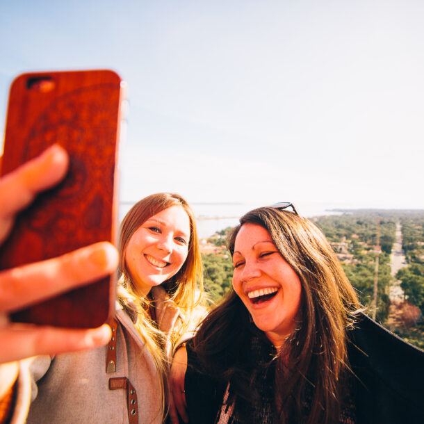Deux amies, remplies de joie, immortalisent leur moment au sommet du phare en prenant une photo souvenir, avec une vue imprenable qui ajoute à la magie de l'instant.