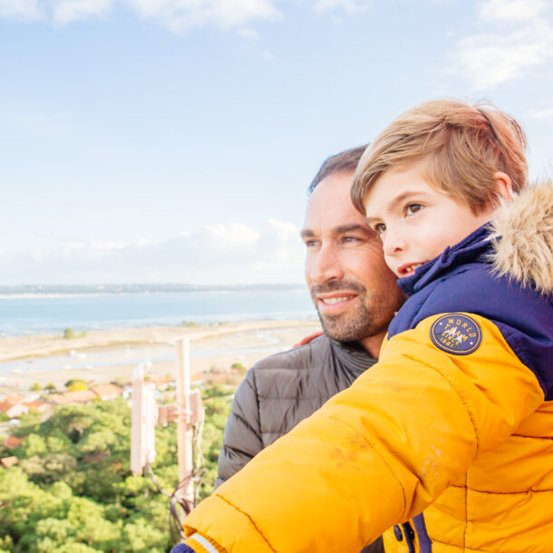 Un homme avec son enfant sont au sommet du Phare en hiver.