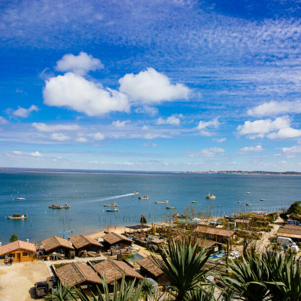 Vue sur le village de l'Herbe avec des cabanes de pêches et le bassin en fond.