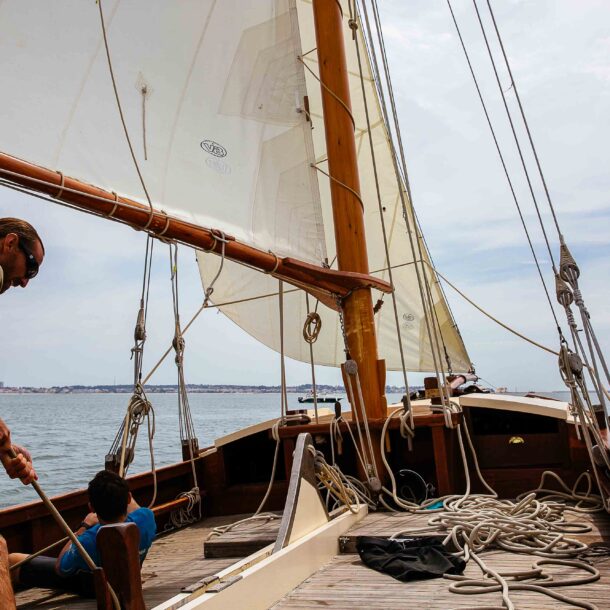 Un homme tire sa voile sur son voilier pour prendre de la vitesse.