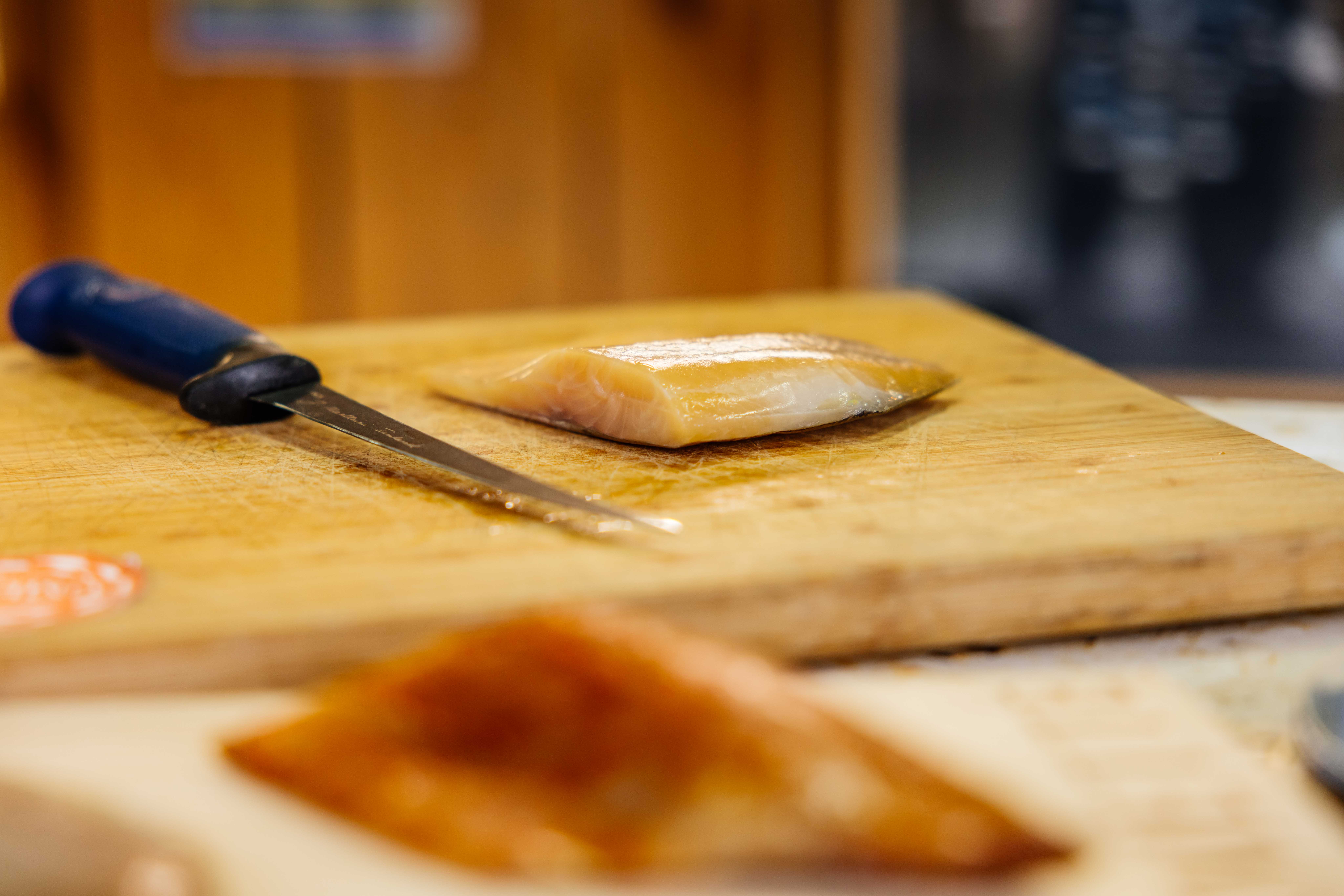 Un poisson fumée sur un planche avec un couteau à côté.