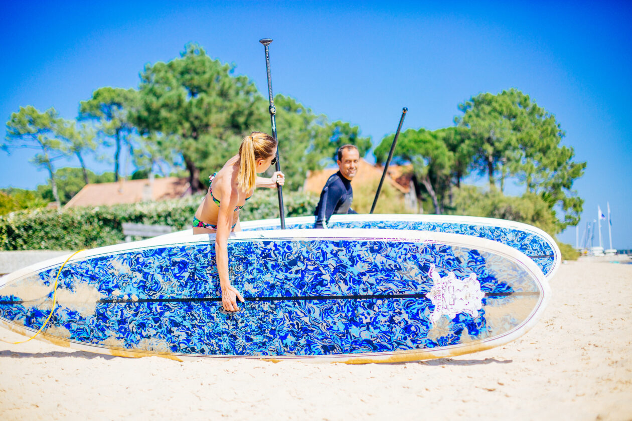 Deux personnes se préparent à faire du paddle sur le bassin.