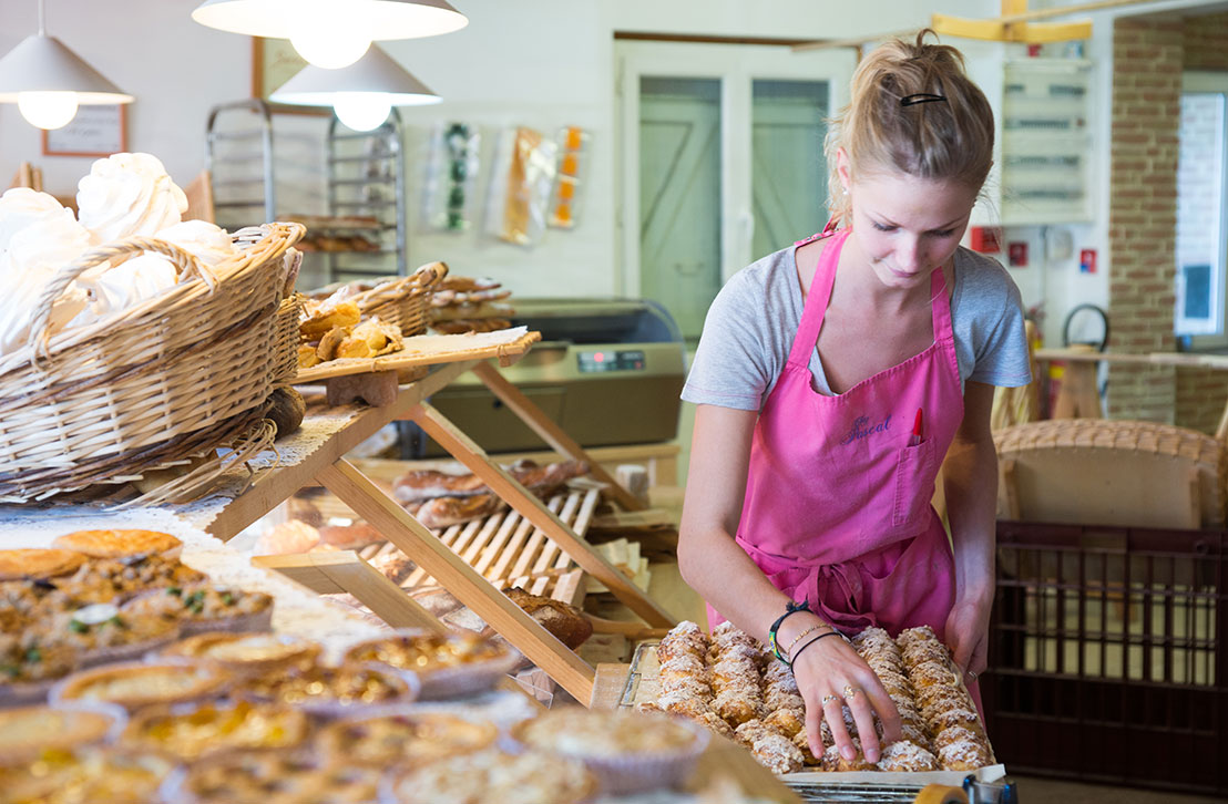Une jeune femme qui sert des dunes blanches à un client dans une boulangerie de Lège-Cap Ferret